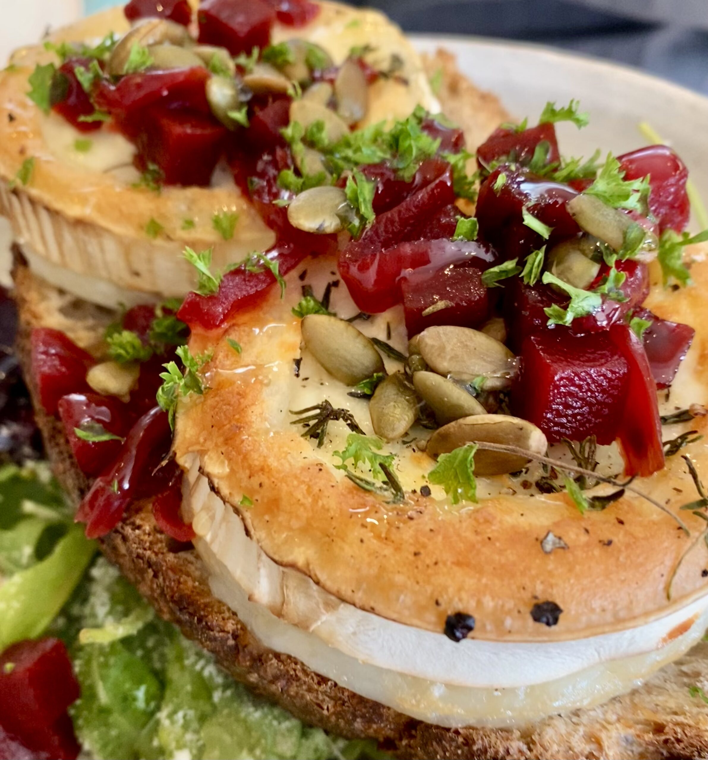 Goat's Cheese Salad. Golden-brown goat's cheese atop crispy bread. On top of the goat's cheese is juicy pickled beetroot cubes, and toasted pumpkin seeds.